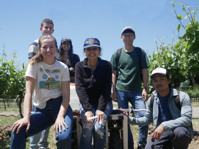 Students stand in a field with a robot