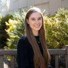 Morgan Johnson sits on a bench in front of yellow and green flowers