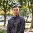 Photo of Graduate Student Willian Huber in professional attire with trees in the background. 